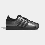Championes Adidas Superstar II, modelo clásico de caña baja en color plateado metalizado con detalles en negro, incluyendo las tres tiras icónicas, los cordones, la suela y el refuerzo del talón. Cuentan con la tradicional puntera de caucho con relieve y exterior de cuero.