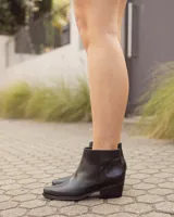 Botas altas negras de cuero, con diseño de caña desmontable de gamuza, punta fina y taco cuadrado bajo estilo texano.