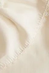 Blusa de viscosa con acabado satinado, cuello Peter Pan fruncido con detalle de encaje, frente abierto con cierre de triple tira y mangas cortas abullonadas con puños elásticos.