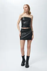 Top strapless negro en símil cuero con costuras tipo corsé y apliques de tachas, cuenta con un cierre metálico a la vista en la espalda.