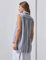 Camisa sin mangas de corte recto, con cuello clásico y escote en V. Presenta un diseño de rayas verticales en tonos lila, rosa, blanco y gris, con dos bolsillos frontales aplicados con estampado en chevron. Cuenta con cierre central de botones.