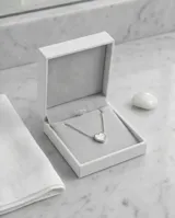 Collar de acero con cadena fina y dije pasante en forma de corazón con incrustación de nácar.
