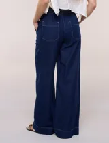 Jean de tiro alto y pierna amplia de corte wide leg, confeccionado en denim azul. Presenta cintura plana en el frente y elastizada en la espalda, bolsillos delanteros aplicados estilo parche y pespuntes a contrapunto.
