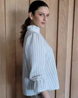 Blusa de algodón con cuello mao y volados, mangas largas con puños elásticos y corte holgado.