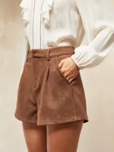 Short de gamuza color marrón, con diseño de tiro alto, pinzas frontales y bolsillos laterales.
