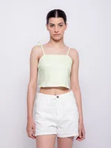 Top corto con escote recto y tirantes finos ajustables mediante nudo en los hombros. Presenta un estampado floral sobre fondo oscuro, con flores rosadas y hojas turquesas.