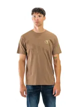 Remera de manga corta color marrón claro (tostado/café con leche) con cuello redondo. Presenta un pequeño logo dorado con las iniciales 'SF' en el pecho izquierdo.