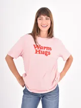 Remera de algodón color rosado con estampa frontal en color rojo con la frase Warm Hugs en tipografía retro.