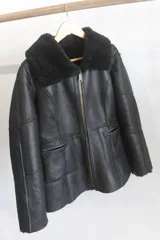 Campera reversible de cuero genuino napalán color negro, con cuello y detalles de corderito sintético, cierre frontal y bolsillos ribeteados.