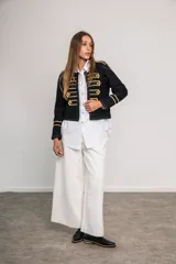 Chaqueta corta negra de paño con corte entallado, detalles dorados bordados, botones metálicos y cuello redondo.