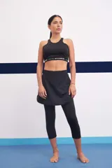 Calza capri negra con falda corta superpuesta.