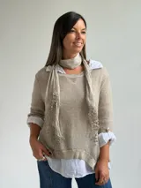 Sweater de punto fino en color beige, con cuello redondo y mangas tres cuartos. El diseño incluye una bufanda integrada del mismo tejido con detalles de puntilla en los extremos.