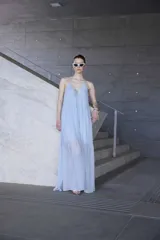 Vestido largo celeste de tirantes finos con escote en V y cordón ajustable en el pecho. Presenta un diseño fluido con falda amplia de capas semitransparentes.