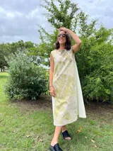 Vestido midi de corte evasé con estampado de hojas en tonos verdes y beige.