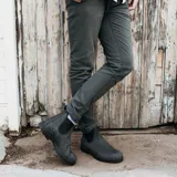 Botas tipo Chelsea Blundstone modelo 587, confeccionadas en cuero nobuck color negro rústico. Presentan puntera cuadrada, elásticos laterales negros y tiradores en la parte superior para facilitar el calce. Cuentan con suela de TPU de alta durabilidad y sistema de amortiguación en el talón.