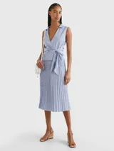 Blusa sin mangas con cuello camisero, diseño cruzado con lazo en la cintura y estampado a rayas verticales azules y blancas.