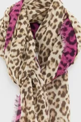 Bufanda de algodón con estampado de animal print tipo leopardo en tonos beige y marrón, combinada con franjas laterales fucsias con el mismo patrón. Presenta bordes desflecados y etiqueta con logo de la marca.