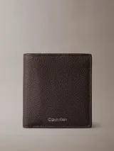 Billetera plegable Calvin Klein de cuero con textura granulada. Cuenta con compartimento para billetes, cinco ranuras para tarjetas y una solapa transparente para identificación. Incluye logo de la marca grabado en lámina metálica.