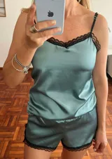 Conjunto de pijama color celeste de satén, compuesto por un top con tirantes finos y detalle de encaje negro en el escote, y un short con elástico en la cintura y detalle de encaje negro en el ruedo.