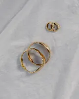 Brazalete rígido de diseño orgánico con textura irregular y acabado brillante, elaborado artesanalmente en metales nobles.