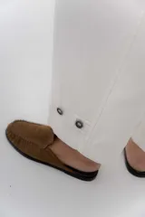 Pantalón de gabardina de algodón color negro, con calce barrel, cintura media baja, recortes de diseño y detalle de botones en el ruedo para ajustar el volumen.