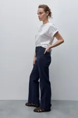 Pantalón de jean azul marino, de tiro alto y calce ajustado con pierna recta levemente amplia, bolsillos traseros y recortes verticales en el delantero.
