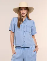 Camisa de corte recto y calce fluido color celeste, confeccionada en lyocell con efecto lavado, cuello camisero tradicional, botones a tono, dos bolsillos aplicados en el pecho y mangas cortas.
