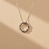 Collar de plata 925 con cadena fina de eslabones y dije circular con diseño trenzado.