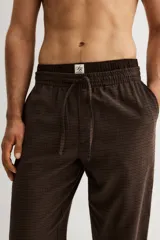 Pantalón de franela de algodón suave, color marrón con patrón de cuadros pequeños. Cuenta con cintura elástica con cordón ajustable y bolsillos al bies. El corte es relajado, pero no oversized.