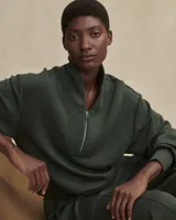 Buzo de tejido ligero DoubleSoft®, color verde oliva, con cuello alto y cierre frontal parcial. Presenta un corte ligeramente recortado, hombros caídos y puños pronunciados.