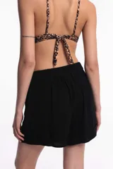 Short negro de algodón con pinzas, tiro alto, pretina con botón frontal y bolsillos laterales.