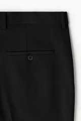Pantalón de vestir negro, corte slim fit, con cierre y botón frontal, bolsillos laterales y bolsillos insertados traseros con botón. Presenta raya marcada en las piernas.
