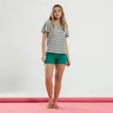 Blusa blanca con estampado de flores azules y verdes, cuello redondo con abertura en forma de gota y mangas cortas amplias.
