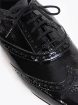 Zapato de cuero vacuno color blanco con acabado arrugado, diseño estilo oxford con detalles perforados, cordones y tacón bajo decorado con pedrería.