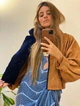 Campera oversize de cuero tostado con solapas y forro interno de corderito sintético azul marino, mangas anchas y detalles de costuras trenzadas.