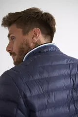 Campera puffer de nylon color azul marino, con cierre frontal completo, cuello alto y puños con detalle de rayas. Cuenta con bolsillos laterales con cierre y logo estampado en el pecho.