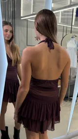 Vestido corto bordó con escote halter, diseño ajustado en el torso de tela translúcida y falda corta con doble volante fruncido.