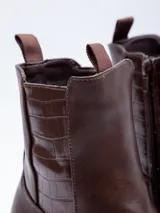 Bota de caña corta color negro, de símil cuero, con plataforma de 7 cm de alto. Cuenta con cierre y pieza de textura croco en laterales.