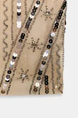 Top de tirantes finos color beige, con escote recto y confeccionado en tul con apliques de lentejuelas negras y plateadas formando patrones geométricos y zigzags.