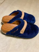 Pantuflas cerradas de cuero azul con detalle de hebilla y suela de goma.
