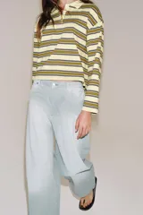 Polo de manga larga confeccionado en algodón, con diseño a rayas horizontales en tonos amarillos, verdes y oscuros. Presenta cuello solapa, cierre frontal con botones y bajo recto.