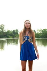 Vestido corto azul con top strapless y detalles de hojas doradas bordadas. Presenta un corte bajo el busto, aberturas laterales en la cintura y breteles finos que se anudan al cuello.