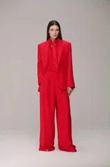 Conjunto de sastrería compuesto por un blazer de corte estructurado con solapas clásicas y un pantalón de vestir de tiro alto, corte recto y pernera ancha con pliegues frontales. Incluye una camisa a tono con corbata integrada.