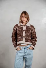 Campera de gamuza con estampado animal print de leopardo, forrada en corderito sintético color crema. Presenta cierre frontal con botones tipo toggle, cuello solapa y detalles de costuras visibles.