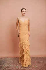 Vestido largo de fiesta color tostado, con escote en V, tirantes finos, cuerpo drapeado y falda sirena con múltiples volados en cascada.