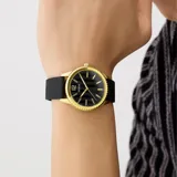 Reloj analógico Guess con caja redonda de acero en tono dorado y esfera negra con acabado texturizado. Cuenta con índices y manecillas doradas, y correa de silicona negra.