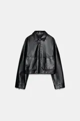 Cazadora corta de efecto piel negra, con cuello solapa, cierre frontal de cremallera y dos bolsillos delanteros de plastrón. Presenta un acabado con efecto lavado y mangas largas.