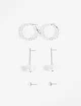 Set de tres pares de caravanas plateadas con perlas: aros tipo argolla con perlas, aros colgantes con perla irregular y aros pequeños con perlas.