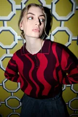 Sweater de tejido de punto con cuello polo y tapeta de botones, presentando un diseño de rayas onduladas anchas en dos tonos de verde.