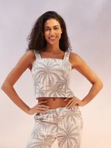 Musculosa corta blanca con estampado de palmeras en tonos grises y beige, con tirantes anchos y escote cuadrado.